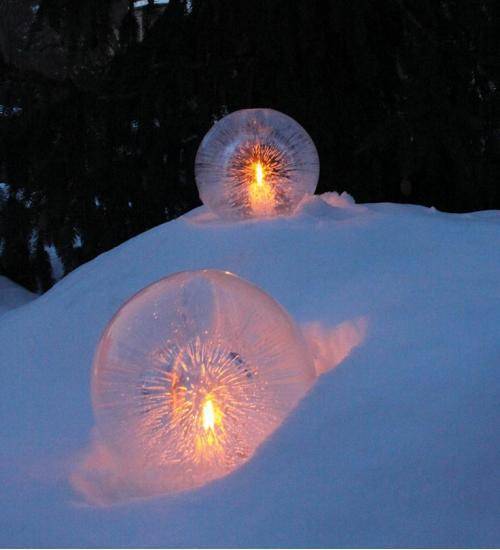 Water balloons half frozen with candles placed in the hollow center