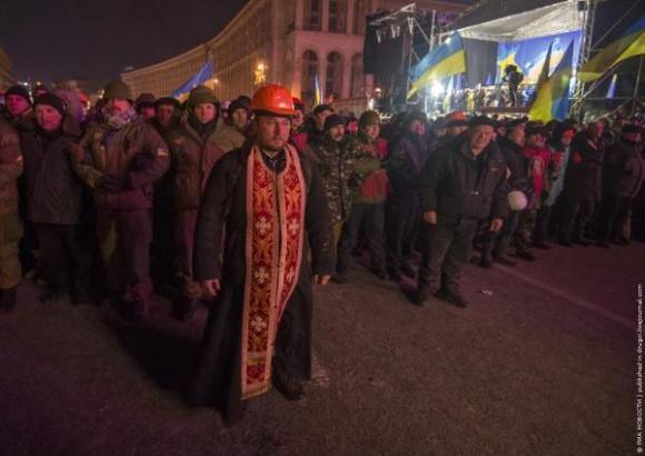 Priest defending rioters from police forces, Kiev, Ukraine.