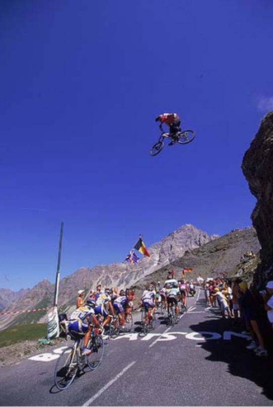 Mountain biker jumps over Tour de France bikers.