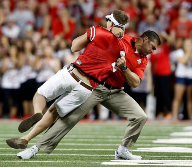 During the Ohio State football game, someone ran out onto the field. One of the Ohio State coaches stopped him.