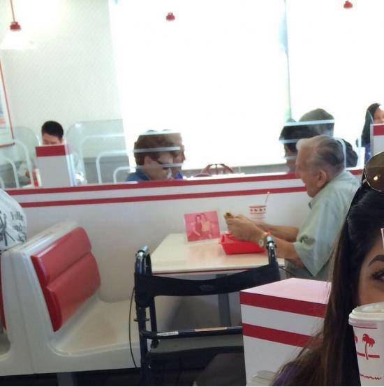 Old man eating by himself at In N Out with a picture of his wife.