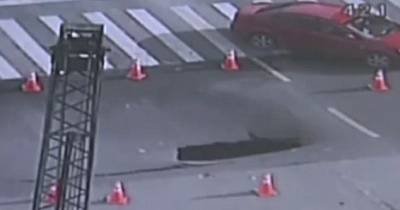 Police Officer Diverts Traffic Around A Crack In Busy Road In China Seconds Before A Six Foot Sinkhole Opens Up